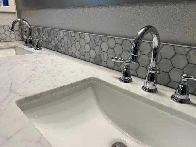 Hexagon mosaic tile backsplash behind a bathroom sink and faucet