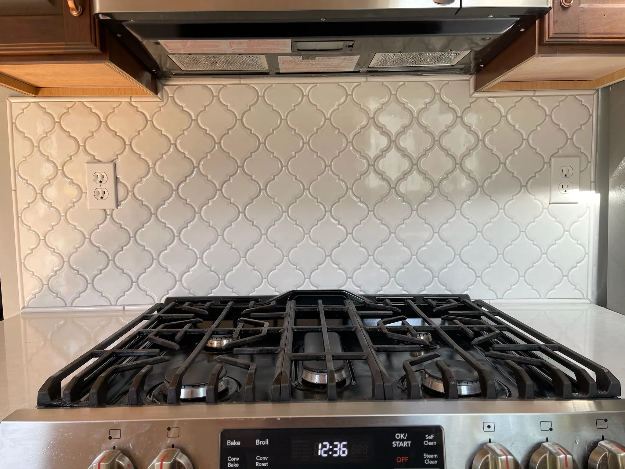 White herringbone tile backsplash installed behind a kitchen stove