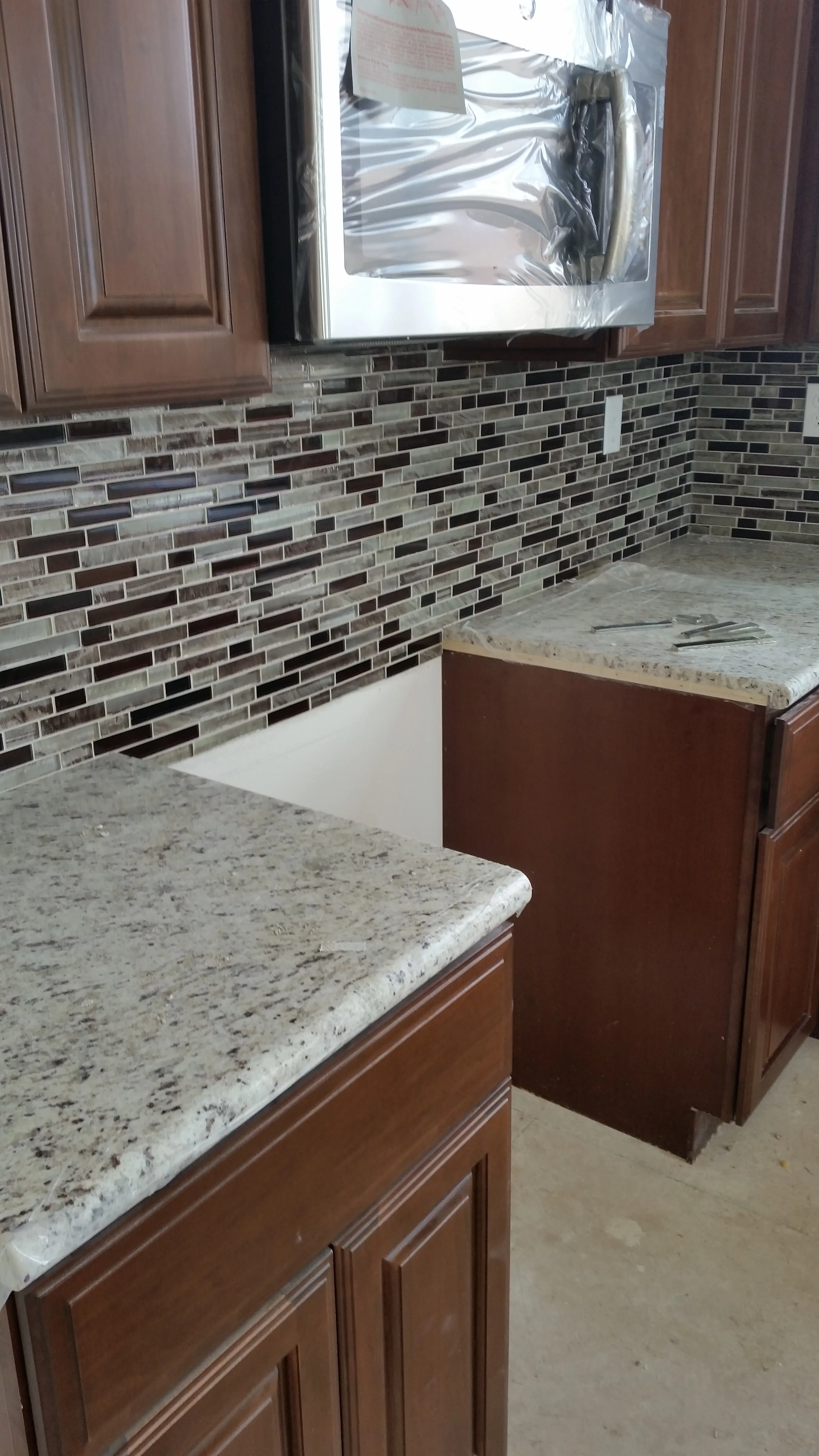 Glass mosaic tile backsplash along a kitchen countertop beneath cabinets